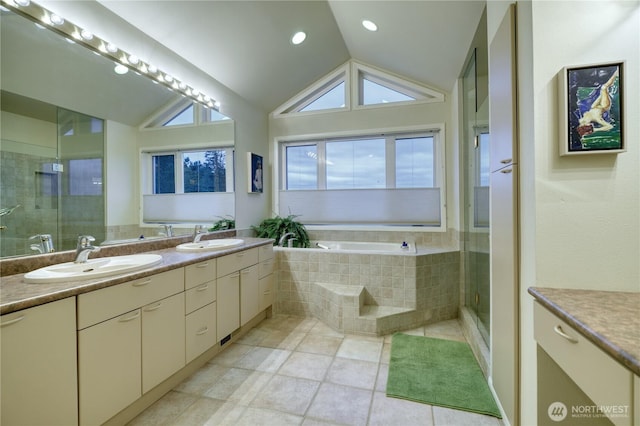 bathroom featuring vaulted ceiling, double vanity, a stall shower, and a sink