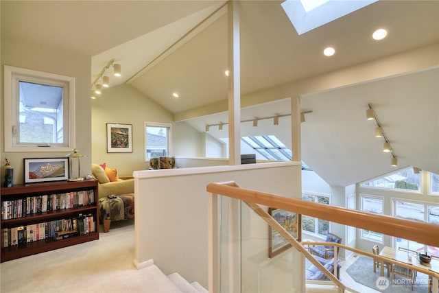 corridor with vaulted ceiling with skylight, recessed lighting, light colored carpet, an upstairs landing, and rail lighting