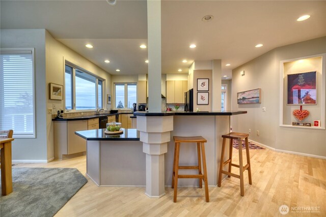 kitchen featuring recessed lighting, a kitchen island, light wood-style floors, black appliances, and dark countertops