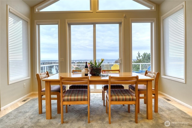 dining space with visible vents, vaulted ceiling, baseboards, and wood finished floors