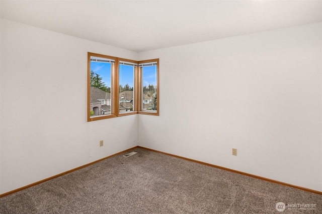 unfurnished room with carpet, visible vents, and baseboards