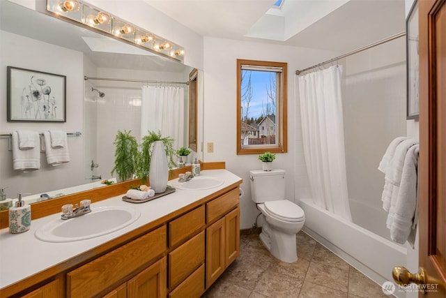 full bathroom featuring shower / bath combination with curtain, a skylight, a sink, and toilet