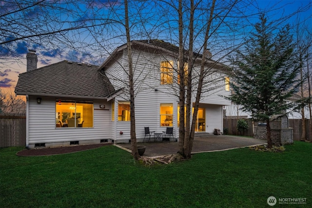 back of house at dusk with a yard, a patio, a chimney, and fence