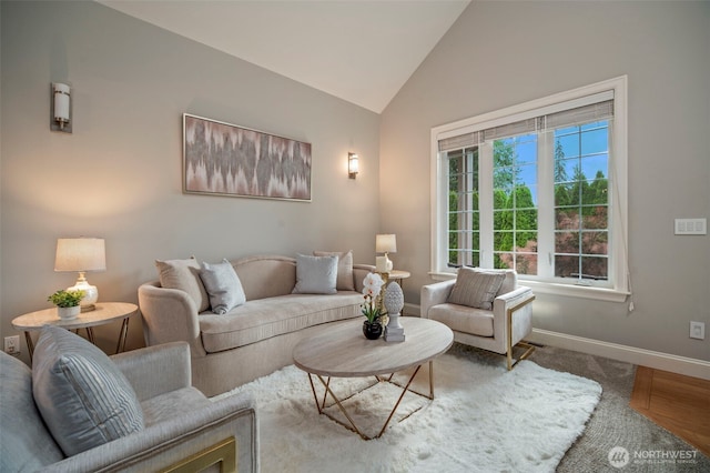 living room featuring lofted ceiling, baseboards, and wood finished floors