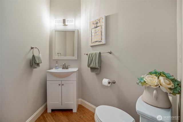 bathroom with toilet, vanity, baseboards, and wood finished floors