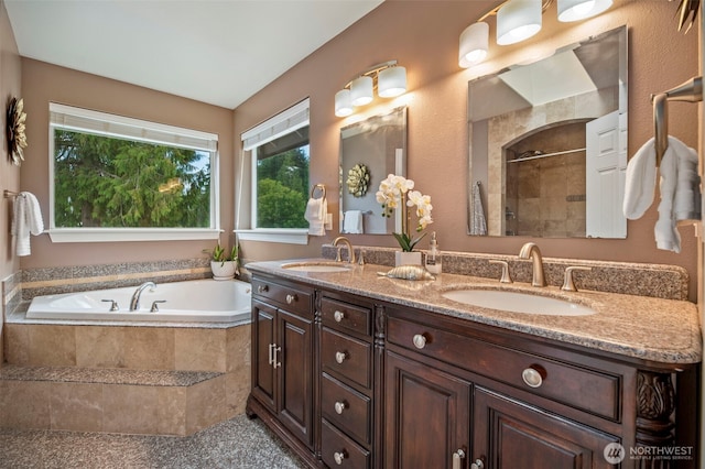 full bathroom featuring double vanity, a stall shower, a sink, and a bath