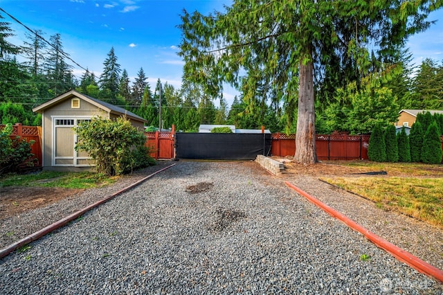 view of yard with an outbuilding, driveway, and fence