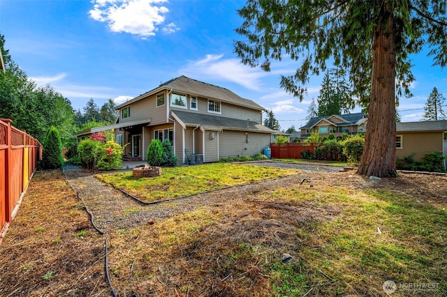 back of property featuring an outdoor fire pit, a fenced backyard, and a yard