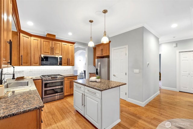 kitchen featuring a center island, arched walkways, stainless steel appliances, brown cabinetry, and a sink