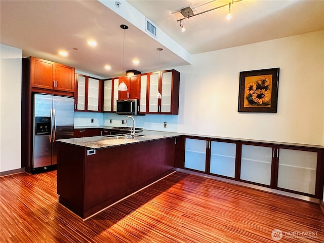 kitchen featuring visible vents, glass insert cabinets, appliances with stainless steel finishes, light stone counters, and hanging light fixtures