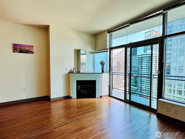 unfurnished living room featuring expansive windows, a fireplace, a city view, and wood finished floors