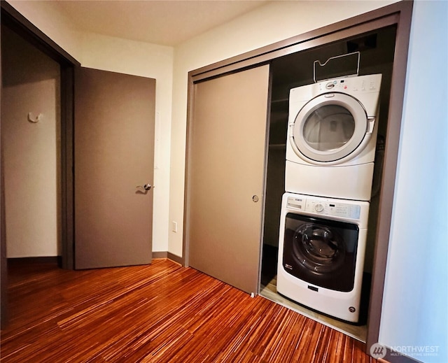 laundry area with laundry area, wood finished floors, and stacked washer and clothes dryer