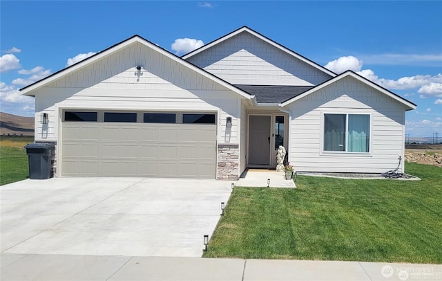 view of front facade with a garage, concrete driveway, a front lawn, and a shingled roof