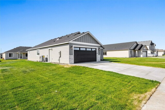 1138 8th Ave NE, Ephrata, WA 98823 - view of side of property featuring board and batten siding, a lawn, driveway, and a garage