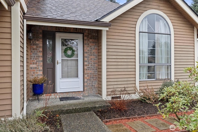 doorway to property with a shingled roof, crawl space, and brick siding