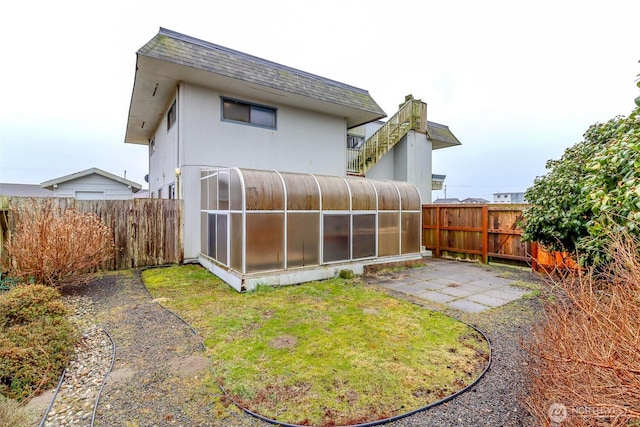 rear view of house with a shingled roof, a patio area, and a fenced backyard