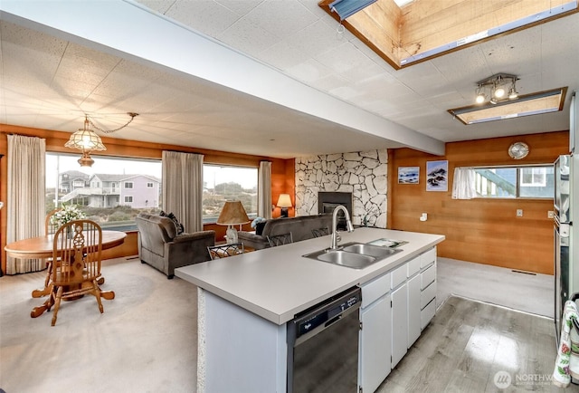 kitchen featuring light countertops, open floor plan, white cabinets, a sink, and dishwasher