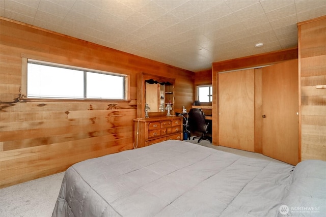 bedroom featuring a closet, multiple windows, and wooden walls