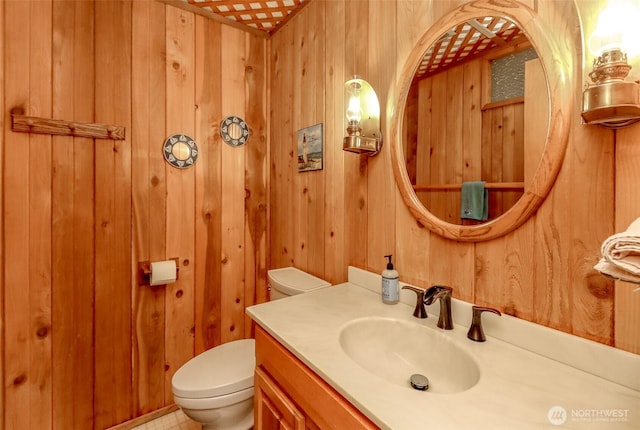 half bath with wooden walls, vanity, and toilet