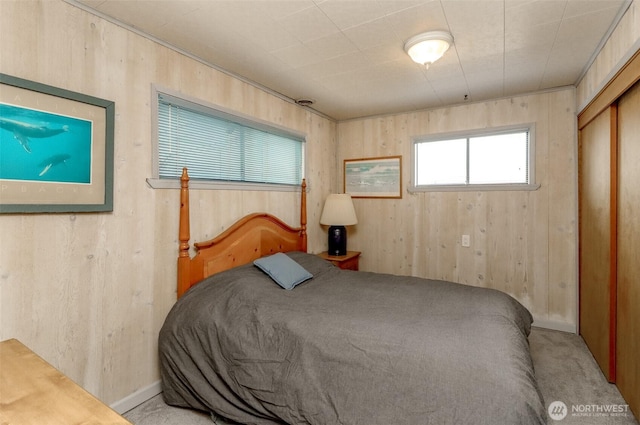 carpeted bedroom featuring wood walls and a closet