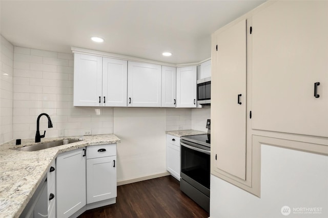 kitchen featuring dark wood-style floors, tasteful backsplash, appliances with stainless steel finishes, a sink, and light stone countertops