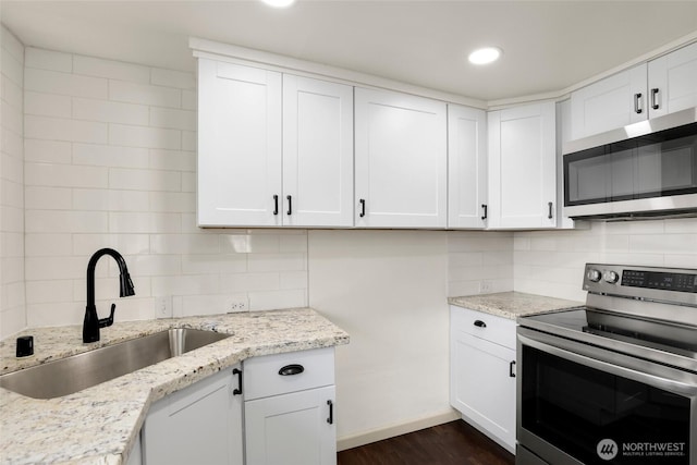 kitchen with stainless steel appliances, white cabinetry, a sink, and decorative backsplash