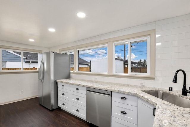 kitchen with white cabinets, appliances with stainless steel finishes, dark wood-style flooring, a sink, and backsplash