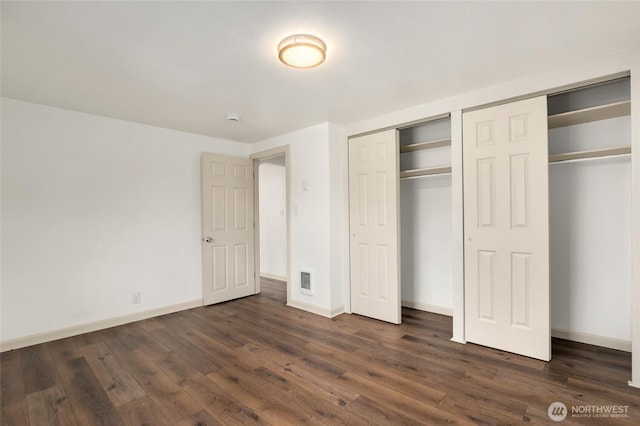 unfurnished bedroom with visible vents, baseboards, and dark wood-type flooring