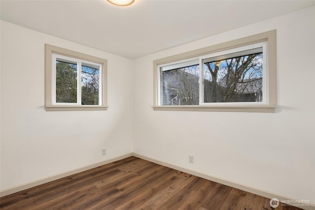 spare room featuring a wealth of natural light, dark wood-style flooring, and baseboards