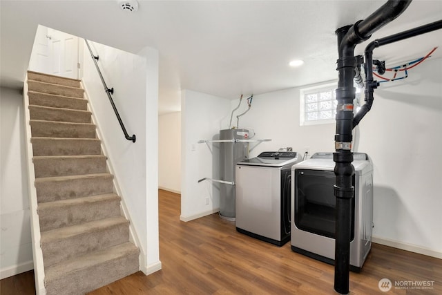 washroom featuring laundry area, wood finished floors, baseboards, water heater, and washing machine and clothes dryer