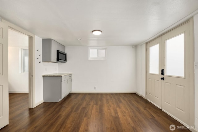 interior space featuring gray cabinetry, light countertops, dark wood finished floors, and baseboards