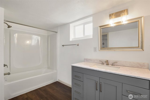 bathroom with a textured ceiling, vanity, wood finished floors, and washtub / shower combination