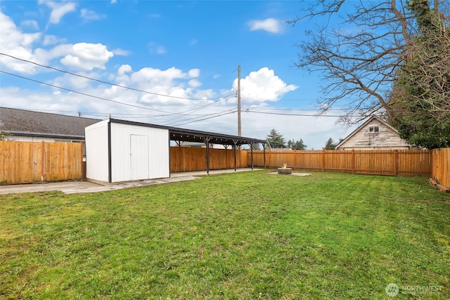 view of yard featuring an outbuilding, a fenced backyard, a fire pit, and a storage unit