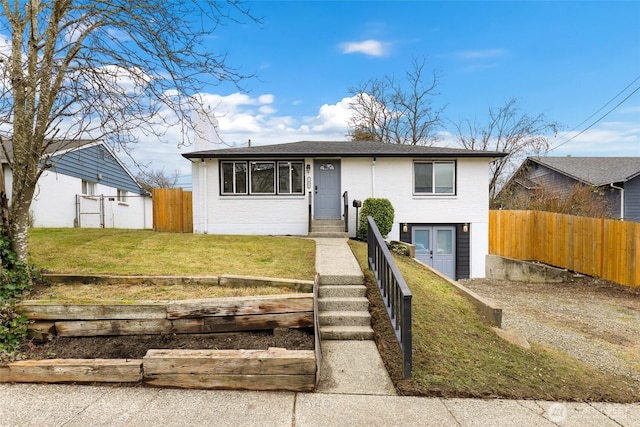 view of front of property featuring brick siding, fence, and a front lawn