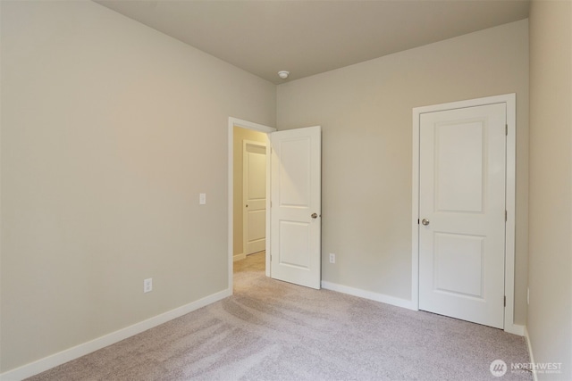 unfurnished bedroom featuring light carpet and baseboards