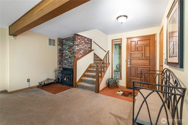 carpeted entryway featuring beam ceiling, stairway, visible vents, and baseboards