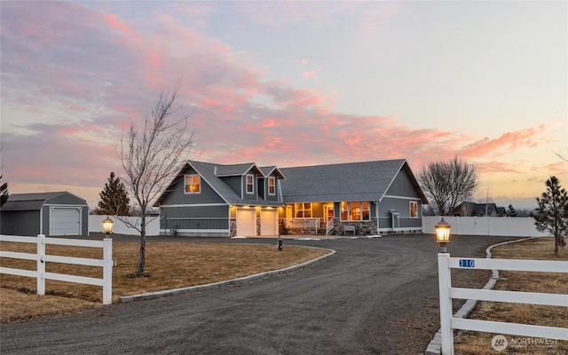 view of front of house with a porch, driveway, a fenced front yard, and a garage