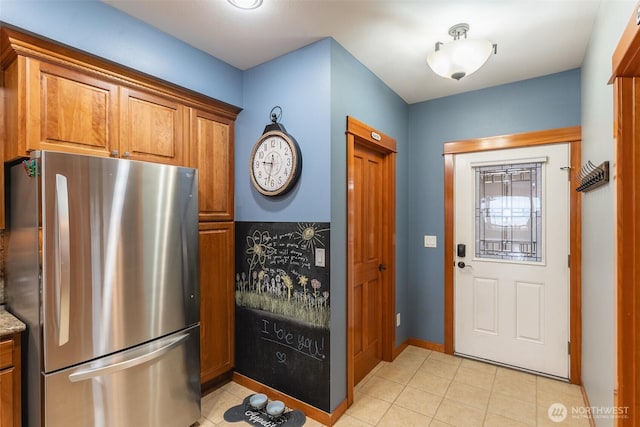 kitchen with brown cabinetry, freestanding refrigerator, light countertops, and baseboards