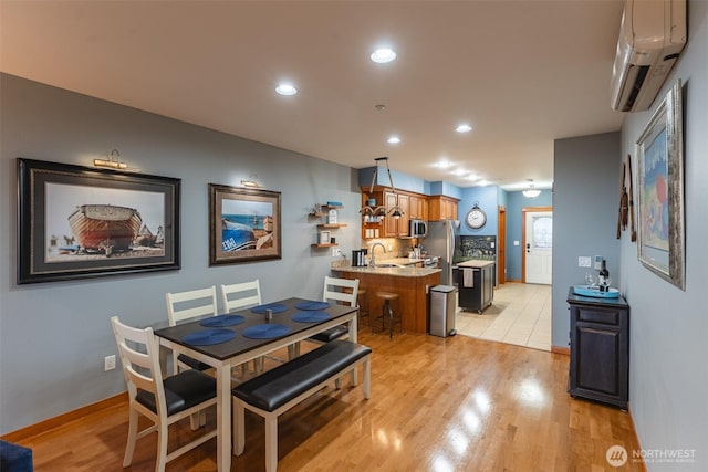 dining area with a wall mounted AC, light wood-style flooring, and recessed lighting