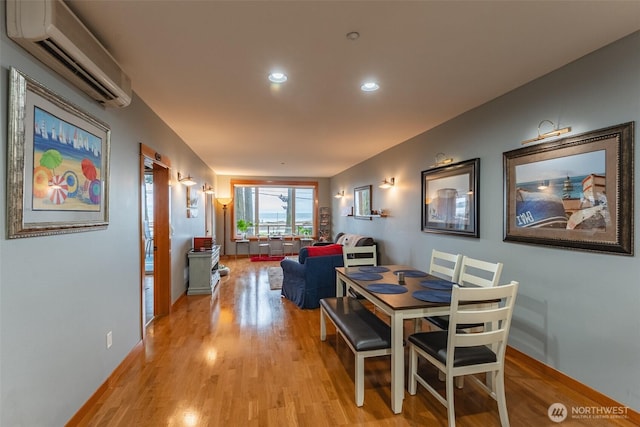 dining area with a wall unit AC, light wood-style floors, baseboards, and recessed lighting