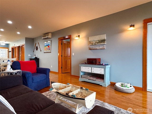 living room with baseboards, a wall unit AC, wood finished floors, and recessed lighting