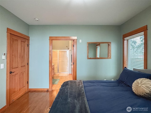 bedroom featuring ensuite bathroom, light wood finished floors, and baseboards