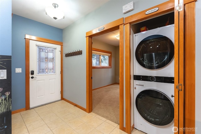 laundry area featuring stacked washer and clothes dryer, light carpet, baseboards, and laundry area