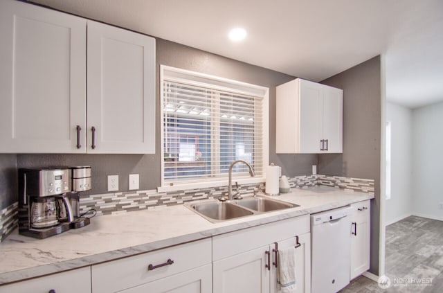 kitchen featuring baseboards, white cabinetry, a sink, and dishwasher