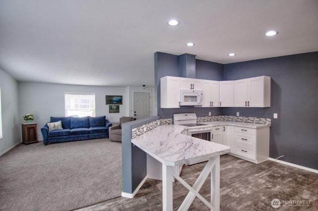 kitchen with open floor plan, white cabinets, white appliances, a peninsula, and baseboards