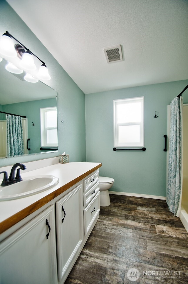 full bathroom featuring toilet, wood finished floors, vanity, visible vents, and baseboards