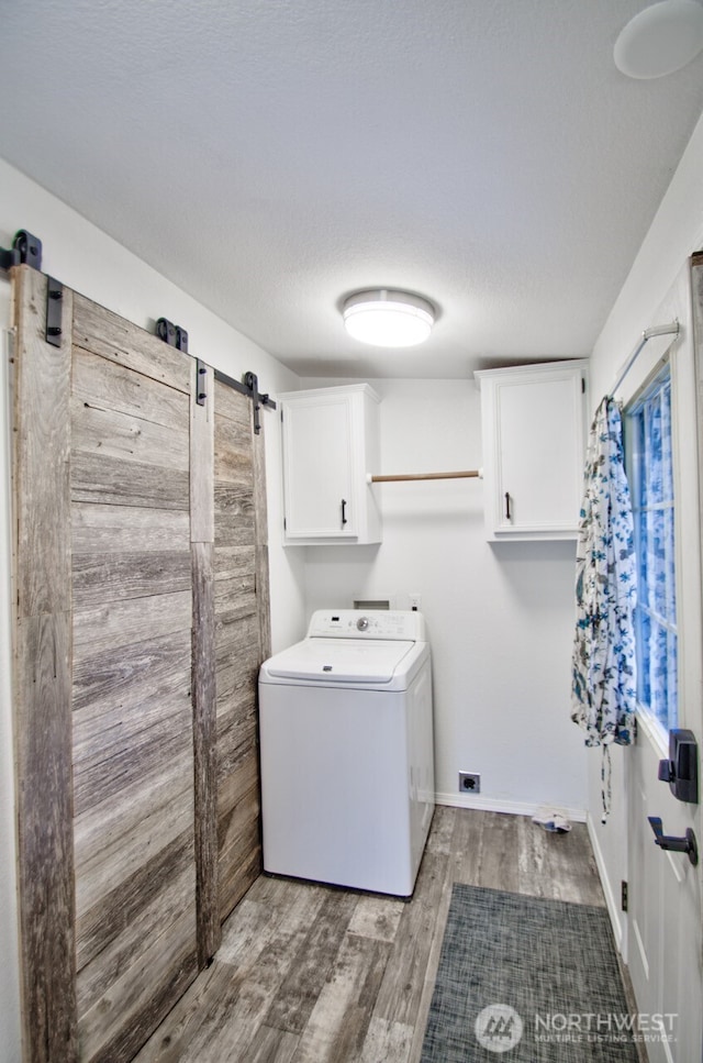 laundry room with a barn door, wood finished floors, baseboards, cabinet space, and washer / clothes dryer