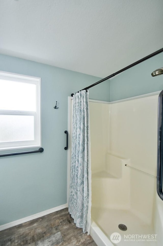 bathroom with a shower stall, baseboards, and wood finished floors