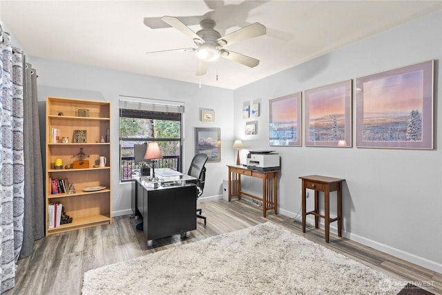 home office with a ceiling fan, baseboards, and wood finished floors