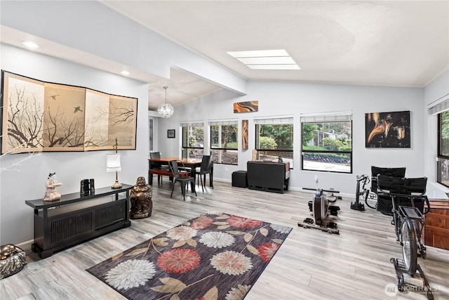 home office with vaulted ceiling with skylight, an inviting chandelier, wood finished floors, and baseboards